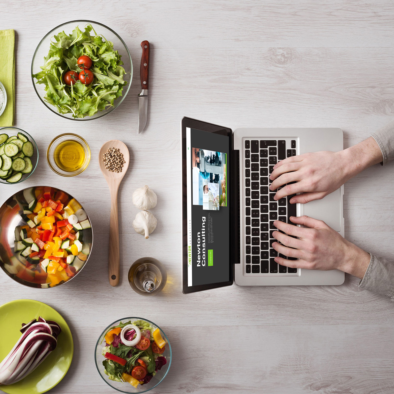 newton-immagine Persona al computer con tutta una serie di alimenti sparsi sul tavolo